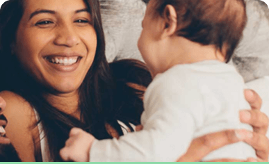 A woman holding an infant, with both looking towards each other.