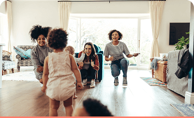 Several people interacting with young children in a bright living room.